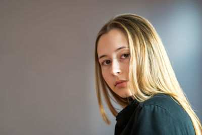 Portrait of beautiful woman standing against gray background