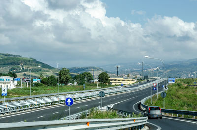 Vehicles on highway against sky in city