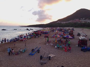 People at beach against sky during sunset