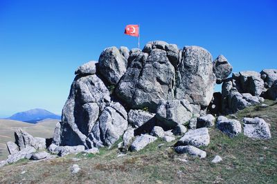 Scenic view of flag on mountains against clear blue sky