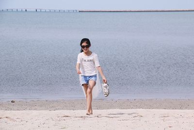 Full length portrait of happy girl walking at beach