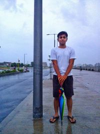 Full length portrait of young man standing against sky