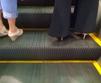 Low section of woman standing on escalator