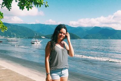 Portrait of smiling young woman standing at beach