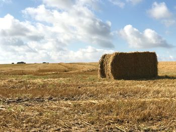 Hay bales on field against sky