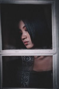 Woman looking away seen through glass window at home