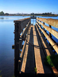 Wooden pier over lake against blue sky