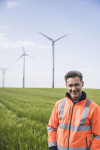 Happy engineer wearing reflective clothing standing on field