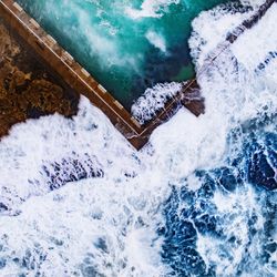 High angle view of waves rushing on fence