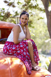 Portrait of smiling woman sitting on vintage car