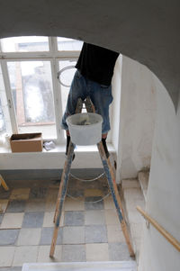 A person climbing up on a stepladder, working at height