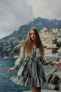Portrait of young woman standing against sky