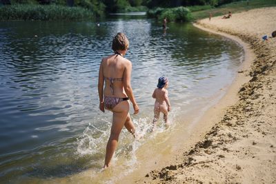 Rear view of young woman and child in water