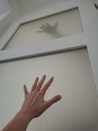 Low angle view of hand on wall