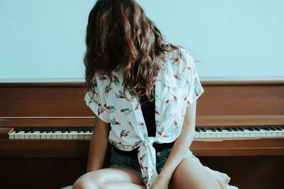 Woman with tangled hair sitting by piano at home