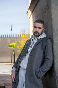 Portrait of young man standing against wall