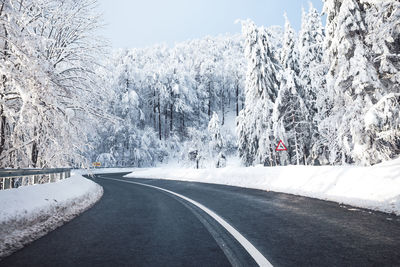 Road amidst snow covered trees 