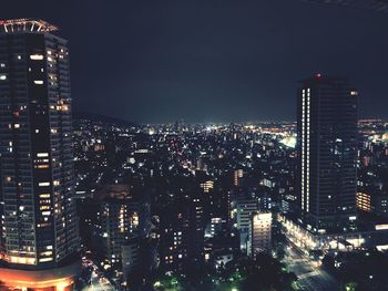 Illuminated cityscape against sky at night