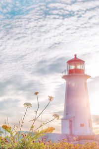 Lighthouse by building against sky