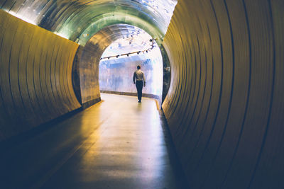 Rear view of man walking in tunnel