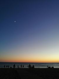 Silhouette of people on beach at sunset