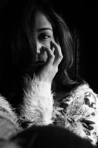 Close-up of young woman with eyes closed against black background