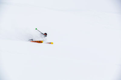 Skier on the piste, going down the slope among the alpine mountains, which are not visible due to