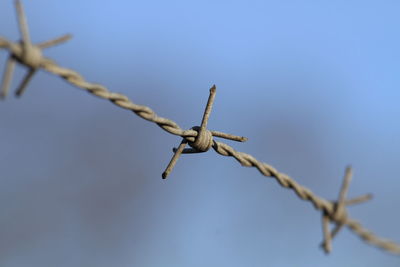 Close-up of barbed wire fence against sky