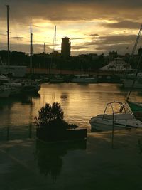 Boats moored at harbor against sky during sunset