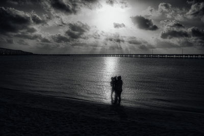 Silhouette people on beach against sky