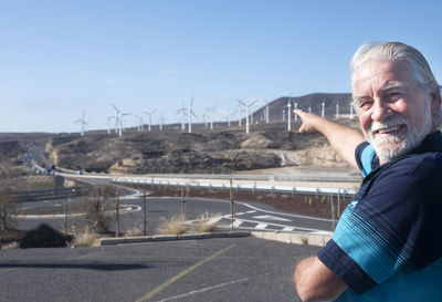 Portrait of smiling man standing on road against sky