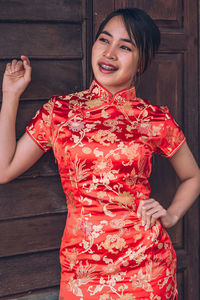 Smiling young woman standing against red wall