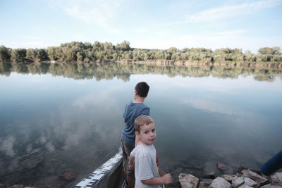 Full length of boys on lake against sky