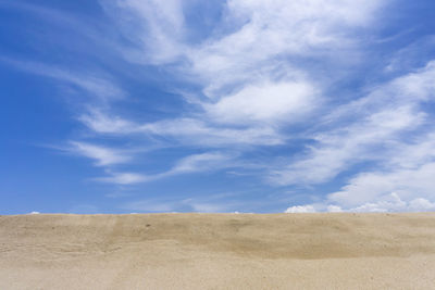 View of sand against blue sky and clouds