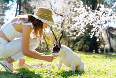 Rear view of woman with dog on grassy field