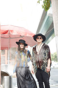 Confident stylish couple in hipster clothes standing on street in summer and looking at camera