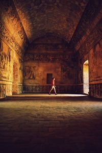 Side view of teenage boy walking in historic building 