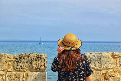 Rear view of woman standing by sea against sky