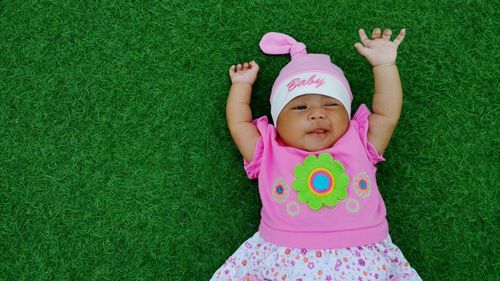 High angle view of baby girl lying on grass