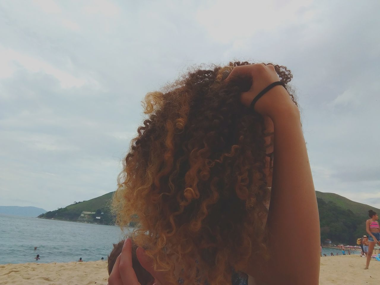 real people, one person, leisure activity, sky, lifestyles, day, long hair, outdoors, focus on foreground, nature, cloud - sky, young women, headshot, sea, beach, curly hair, women, water, mountain, young adult, vacations, beauty in nature, childhood, close-up, people