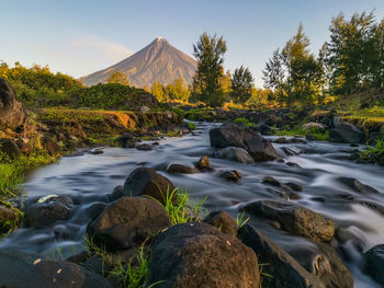 Scenic view of rocks by river against sky
