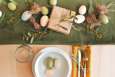 Easter holiday table setting - white dinner plates with easter eggs and festive easter garland