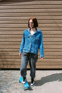 Young stylish woman wears sunglasses walks on the street with a skateboard