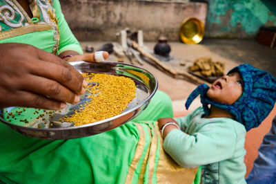 Midsection of woman cleaning food in plate by daughter