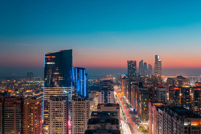 Illuminated cityscape against sky during sunset