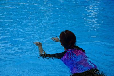 Rear view of woman swimming in pool