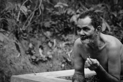 Senior man smoking while standing by retaining wall