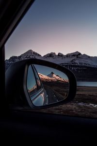 Snowcapped mountains seen on side-view mirror of car