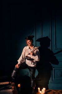 Full length of woman sitting in illuminated hat