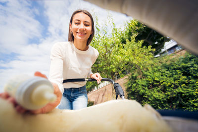 Portrait of smiling young woman sitting on bicycle against sky
